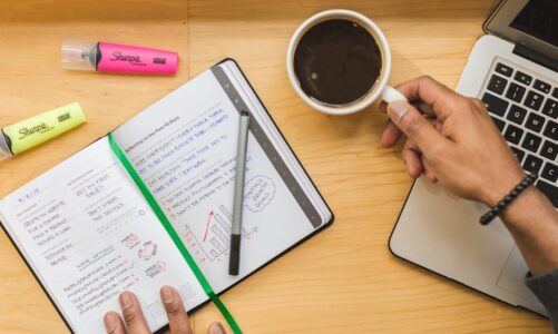 zapisany notes, kawa, zakreślacze i laptop