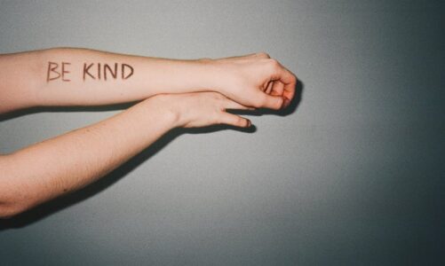 "BE KIND" napisane na ręce