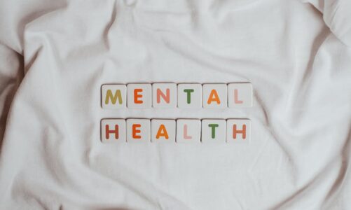 Białe klocki z literami tworzącymi napis MENTAL HEALTH na jasnym tle.